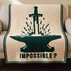 May include: A cream-colored crochet blanket featuring a dark green pixelated graphic of a sword striking an anvil, with the word "IMPOSSIBLE ?" printed below in dark green. The blanket is finished with a dark green border along the edges.