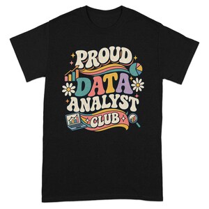 Może przedstawiać: Czarny t-shirt z krótkim rękawem z kolorową grafiką i napisem "PROUD DATA ANALYST CLUB". Wzór zawiera ilustracje laptopa z wykresem, wykres kołowy, lupę oraz małe białe kwiaty stokrotki rozmieszczone wokół centralnego tekstu.