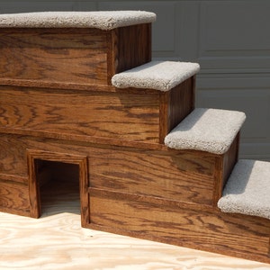 May include: A wooden pet step with four steps, each covered in beige carpet. The steps are angled and have a small opening in the bottom step.