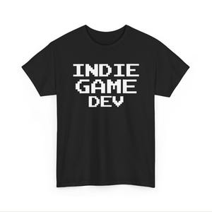May include: A black short-sleeved t-shirt featuring the white pixelated text INDIE GAME DEV centered on the chest. The garment has a crew neckline and a standard fit, showcasing a clean design with bold, blocky lettering in a retro video game style.