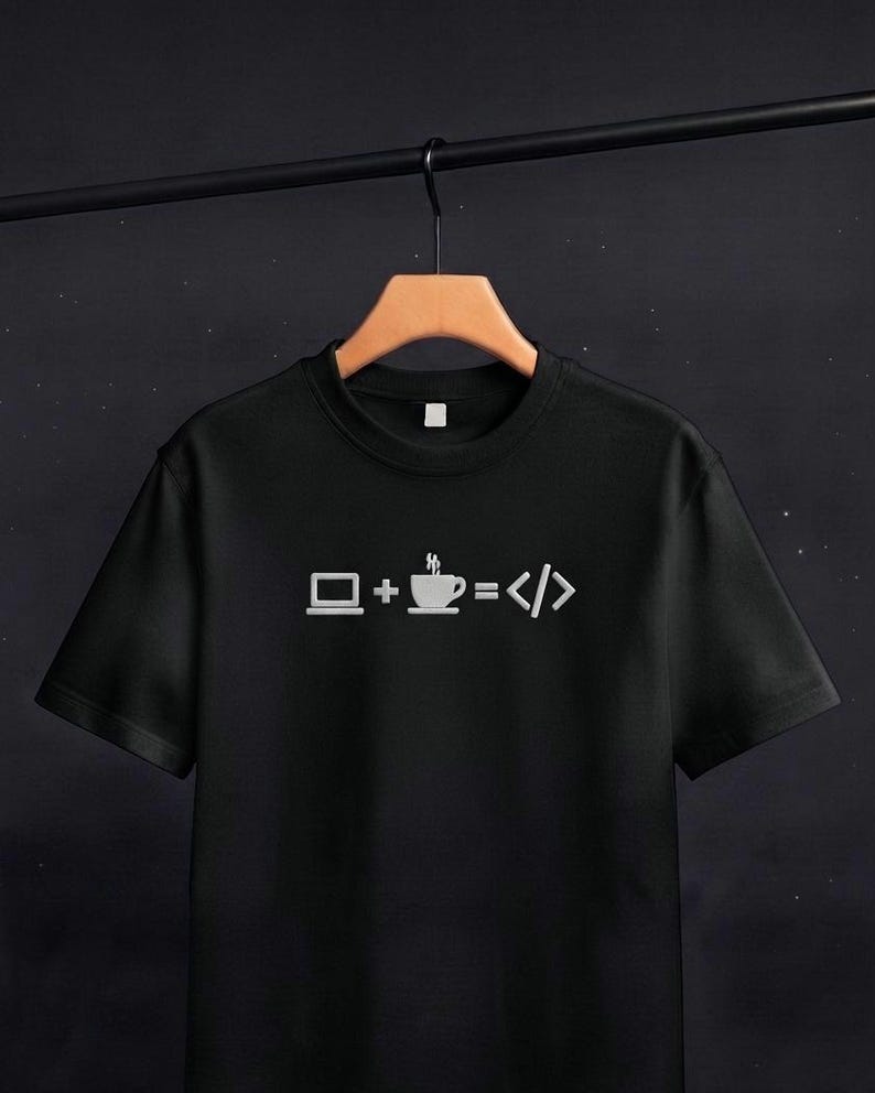 May include: A black short-sleeved t-shirt featuring a white graphic print on the chest. The design displays a laptop icon, a plus sign, a steaming coffee cup icon, an equals sign, and code brackets, representing the equation laptop plus coffee equals code.