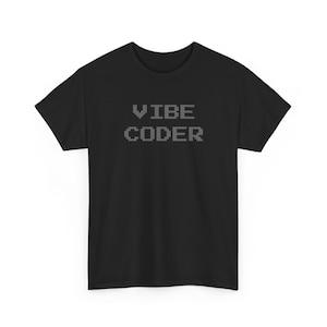 Może przedstawiać: Czarny t-shirt z krótkim rękawem z napisem VIBE CODER nadrukowanym ciemnoszarą, pikselową czcionką na klatce piersiowej. Odzież posiada standardowy okrągły dekolt i prosty dół, wykonana jest z jednolitego czarnego materiału na całej powierzchni.
