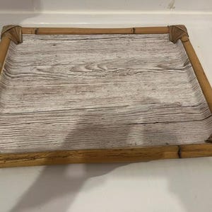 May include: A rectangular serving tray featuring a light brown bamboo frame with woven corner details and a flat base surface printed with a weathered white and grey wood grain pattern. The tray has a low profile and a clean, open design.