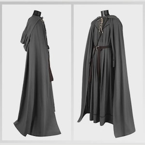 May include: A floor-length dark gray hooded cloak and matching tunic set. The cloak features a hood and a side tie closure. The tunic includes a lace-up neckline with light-colored cords, a dark brown belt with a buckle, and pleated fabric.