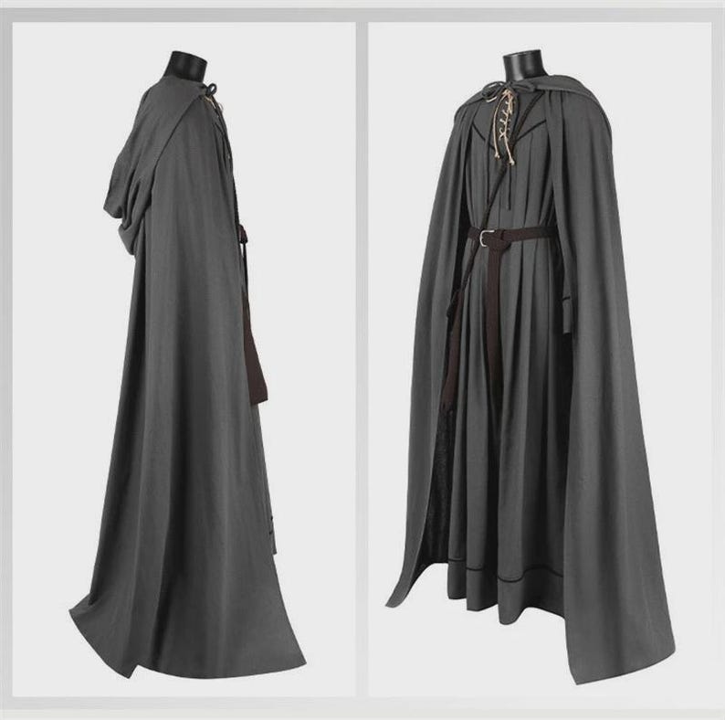 May include: A floor-length dark gray hooded cloak and matching tunic set. The cloak features a hood and a side tie closure. The tunic includes a lace-up neckline with light-colored cords, a dark brown belt with a buckle, and pleated fabric.