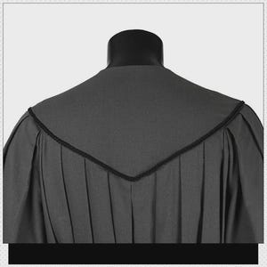 May include: A charcoal gray academic gown featuring a V-shaped yoke across the back and shoulders. The garment is constructed with vertical pleats extending from the yoke down the back, finished with a thin black corded trim along the edges.