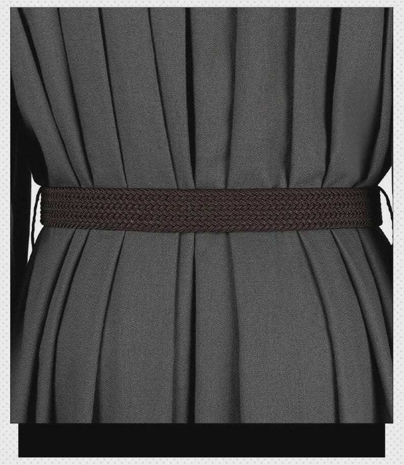 May include: A dark brown braided belt worn over a solid dark gray pleated garment. The belt features a consistent woven texture and is positioned horizontally across the waist area, cinching the fabric of the pleated dress or skirt.