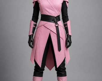 Peut inclure: Une tunique à capuche rose avec un devant croisé, portée sur un haut noir à manches longues et un pantalon noir. La tenue comprend une ceinture noire avec une boucle à anneau, des gants noirs, des protège-bras roses et des bottes noires.