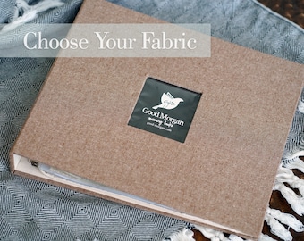 May include: A brown fabric-covered binder with a clear window displaying the text "Good Morgan memory book" and a small bird graphic. The text "Choose Your Fabric" is displayed above the binder.