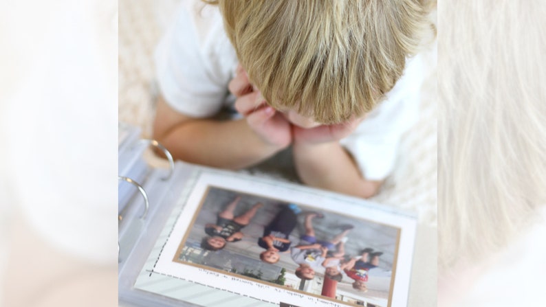 Puede incluir: Un ni&ntilde;o peque&ntilde;o mirando un &aacute;lbum de fotos lleno de fotos de un grupo de ni&ntilde;os. El &aacute;lbum de fotos est&aacute; abierto en una p&aacute;gina con una foto de cinco ni&ntilde;os de pie en fila.