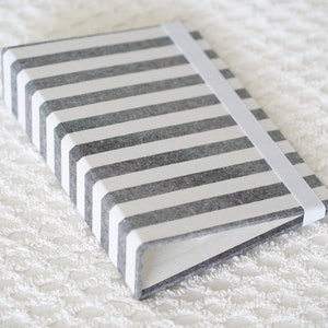 May include: A gray and white striped notebook with a white elastic band closure.
