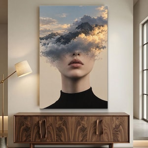 May include: A rectangular wall art print featuring a portrait of a person with a black turtleneck. The upper portion of the face is obscured by a surreal landscape of dark, jagged mountain peaks emerging from a dense layer of golden-lit clouds.