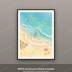 May include: A framed digital art print depicting a sunny beach scene with light blue ocean waves, a sandy shore, a sandcastle, a pink starfish, seashells, and footprints. Two small blue and purple creatures are playing in the shallow water.