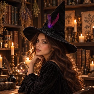 May include: A black velvet witch hat featuring a wide brim and a pointed crown. The hat is adorned with a black fabric flower and two vibrant purple and magenta feathers attached to the front base of the crown, creating a distinct focal point.