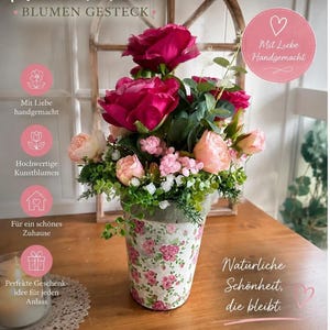 Könnte beinhalten: Ein Blumenarrangement mit dunkelrosa und hellpfirsichfarbenen Rosen und grünem Blattwerk in einem zylindrischen Topf mit rosa Rosenmuster. Das Bild enthält den deutschen Text: Hand Made, Blumen Gesteck, Mit Liebe Handgemacht und Natürliche Schönheit, die bleibt.
