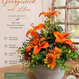 May include: A floral arrangement featuring bright orange lilies and smaller orange daisy-like flowers with green foliage in a round, grey, textured pot. The image includes German text: Grabgesteck mit Lilien, Handarbeit, Mit Liebe für einen besonderen Gedenkmoment, Hochwertige Kunstblumen, Mit Liebe handgefertigt, Dauerhaft schön, Wetterfest & pflegeleicht, Handarbeit, die von Herzen kommt, and a Hand Made stamp.