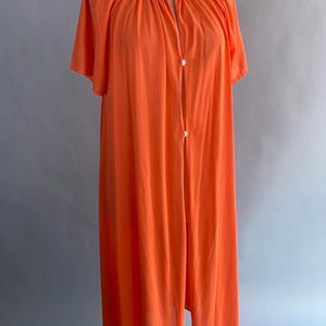 May include: A long, orange, lightweight robe with a button-up front and short sleeves. The robe is made of a soft, sheer fabric.