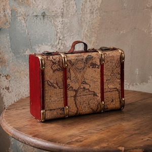 May include: A rectangular suitcase featuring a vintage world map print on the exterior, accented with deep red side panels, a brown leather handle, and brass-toned metal corner reinforcements, latches, and vertical decorative straps.