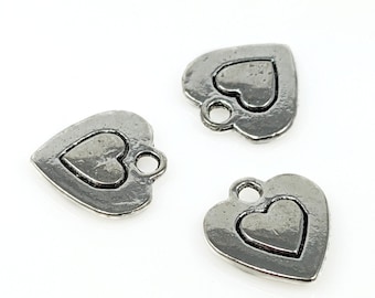 May include: Three silver heart-shaped charms with a smaller heart design inside each. The charms have a loop at the top for attaching to jewelry or other crafts.
