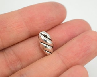 May include: A silver metal bead with a twisted design. The bead is oval shaped and has a smooth, shiny finish.