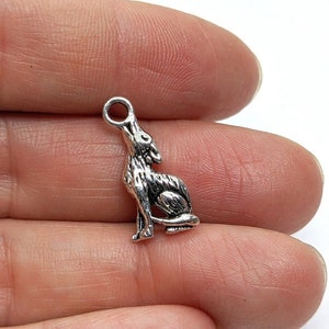 Peut inclure: Breloque en argent représentant un loup assis, avec une boucle en haut pour l'attacher à un collier ou un bracelet.