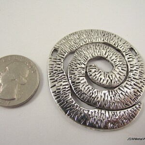 K&ouml;nnte beinhalten: Silberner Metalls Anh&auml;nger mit einem strukturierten Spiralendesign. Der Anh&auml;nger ist etwa so gro&szlig; wie eine US-amerikanische 25-Cent-M&uuml;nze.
