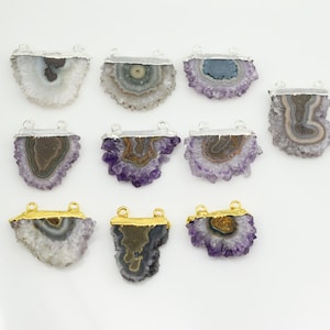 May include: Twelve amethyst crystal pendant charms with silver and gold accents. The charms are in various shapes and sizes, with some featuring a layered, banded pattern.