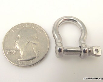 Könnte beinhalten: Ein silberfarbener Metallschackel mit einem Schraubstift. Der Schackel ist etwa so groß wie eine deutsche 2-Euro-Münze.
