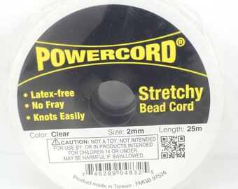 以下が含まれることがあります： 「POWERCORD® Stretchy Bead Cord」とラベル付けされた、透明な伸縮性のあるビーズコードのスプールです。ラテックスフリーで、ほつれにくく、簡単に結ぶことができます。スプールは長さ25メートル、直径2ミリメートルです。ラベルには、「注意：おもちゃではありません。14歳未満のお子様による、または14歳未満のお子様向けの製品での使用を意図していません。飲み込むと有害になる可能性があります。」という警告も記載されています。