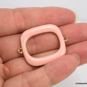 Op de afbeelding: Een roze geëmailleerd metalen frame met goudkleurige randen en springringen. Het frame is rechthoekig met afgeronde hoeken.