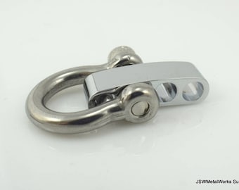 Könnte beinhalten: Ein silberfarbener Metallverschluss mit einem D-Ring und einer Schiebeleiste. Der Verschluss hat drei Löcher in der Leiste zum Befestigen an einem Band oder einer Kette.