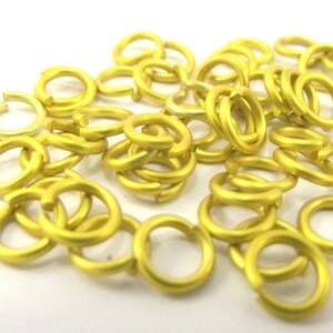 May include: A pile of 50 gold-colored jump rings. The jump rings are approximately 6mm in diameter.