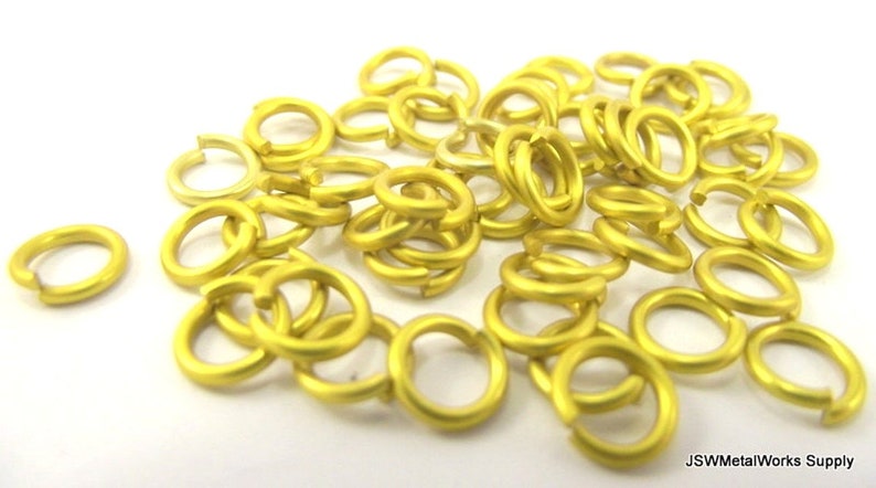 May include: A pile of 50 gold-colored jump rings. The jump rings are approximately 6mm in diameter.