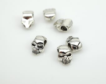 May include: Six silver skull-shaped beads with a hole through the top for stringing. The beads are a popular choice for jewelry making and crafting.