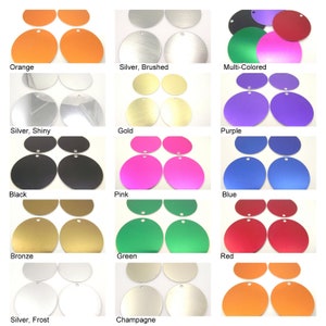 Op de afbeelding: Assortiment van 12 ronde metalen labels in verschillende kleuren met een gat aan de bovenkant. De kleuren omvatten oranje, zilver, veelkleurig, zwart, roze, blauw, brons, groen, rood, champagne en zilver.