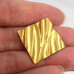 May include: A square piece of gold metal with a textured surface. The metal has a wavy, rippled pattern.