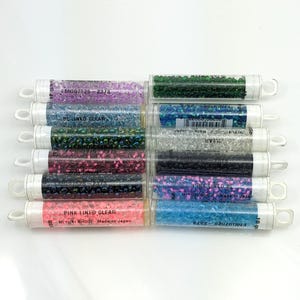 Puede incluir: Diez pequeños tubos de cuentas de semillas Miyuki en varios colores, incluyendo transparente, rosa, verde y azul. Cada tubo está etiquetado con el tamaño de la cuenta, el color y la información del fabricante.
