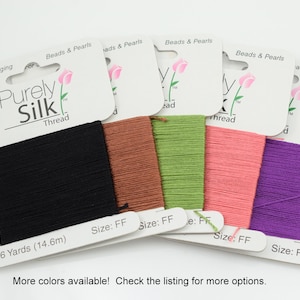 Peut inclure: Plusieurs bobines de fil Purely Silk, de couleurs variées : noir, marron, vert, rose et violet. Chaque bobine porte l'inscription "16 Yards (14.6m)" et "Size: FF". L'emballage indique "Beads & Pearls" et "For Stringing".