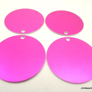 Op de afbeelding: Vier ronde, roze metalen schijven met een gat in het midden. De schijven zijn glad en hebben een lichte glans.