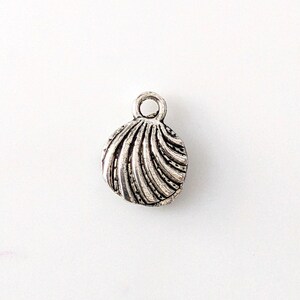 May include: Silver charm in the shape of a seashell with a swirl design.