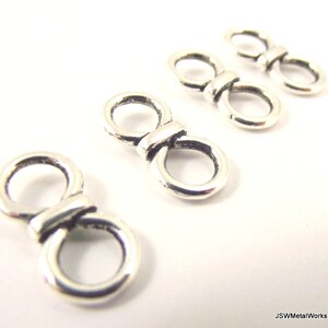 May include: Silver-toned metal figure eight jump rings. The rings are smooth and have a slightly rounded shape. They are ideal for jewelry making and other crafts.