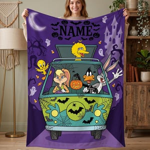 May include: A purple fleece blanket featuring a cartoon van with Looney Tunes characters including Tweety, Lola Bunny, Daffy Duck, Bugs Bunny, and Big Bird. The design includes a Halloween theme with ghosts, bats, a pumpkin, and the word NAME.