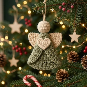 May include: A handmade crochet angel ornament featuring a sage green dress, cream-colored wings, a round cream head, and a central cream heart detail. The ornament hangs from a simple jute twine loop, showcasing intricate yarn stitching throughout.