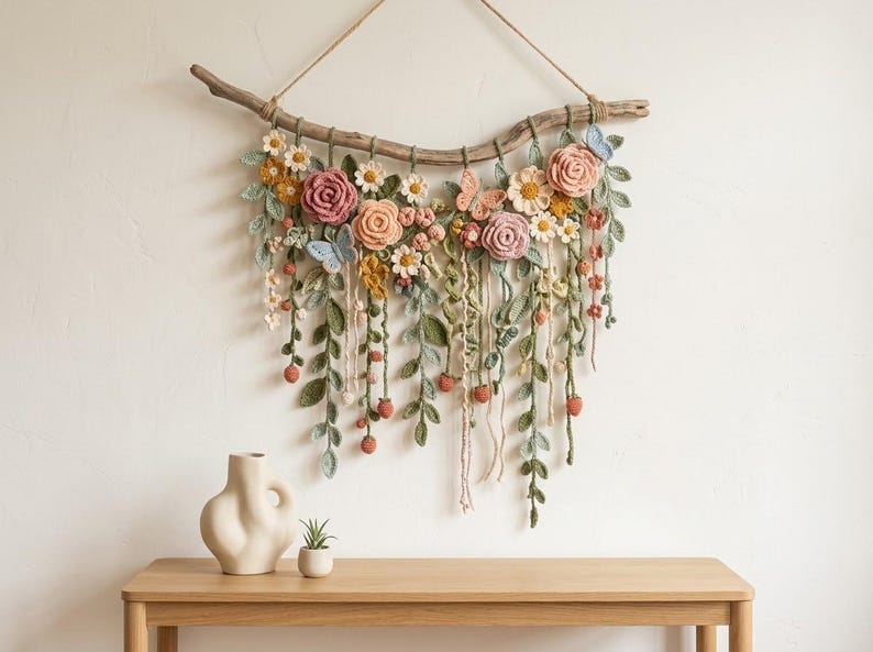 May include: A wall hanging featuring crocheted flowers, leaves, and butterflies in shades of pink, yellow, green, and blue, attached to a natural wooden branch with a jute string for suspension, showcasing intricate yarn textures and floral details.