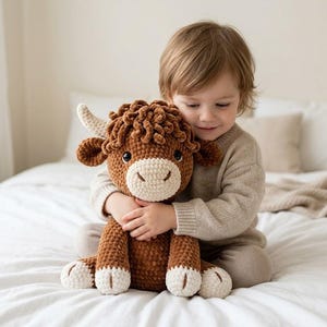 Pode incluir: Um brinquedo de pel&uacute;cia de vaca highland castanha com um corpo de fio texturizado e encaracolado, um focinho cor de creme e pequenos chifres cor de creme. O bicho de pel&uacute;cia apresenta olhos escuros e redondos e detalhes creme nas pontas das quatro patas.