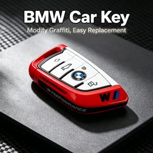 Op de afbeelding: Een rood-witte BMW autosleutelcover met de tekst BMW Car Key, Modify Graffiti, Easy Replacement, Competition en M Performance. De sleutelhanger heeft een glanzend rood frame, een wit knoppenpaneel met zwarte iconen en het BMW-logo.
