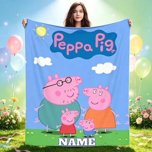 May include: A light blue fleece blanket featuring the Peppa Pig logo at the top, with illustrations of Daddy Pig, Mummy Pig, Peppa Pig, and George Pig in the centre. The bottom of the blanket includes the word NAME in white block letters.