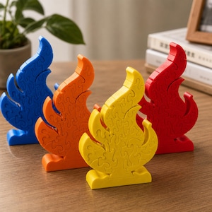 May include: Four flame-shaped puzzles standing upright, each composed of interlocking pieces. The puzzles are colored blue, orange, yellow, and red, and each features a solid base that allows it to stand vertically on a flat surface.