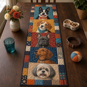 May include: A rectangular quilted table runner featuring five vertical panels, each displaying a different dog breed portrait. The border consists of small patchwork squares in blue, orange, and cream tones with paw print and polka dot patterns.