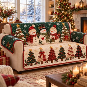 May include: A quilted sofa cover featuring a dark green top section with three snowmen and two Christmas trees, and a cream-colored bottom section with six decorative Christmas trees. The fabric is adorned with white snowflake patterns throughout.